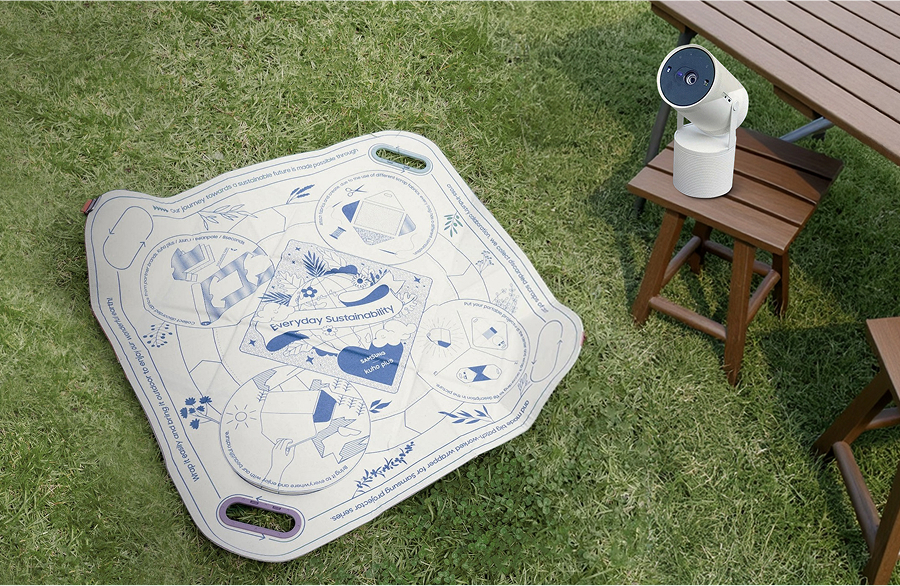 A bojagi spread out on an outdoor lawn, with the Samsung Freestyle placed on a nearby folding chair.