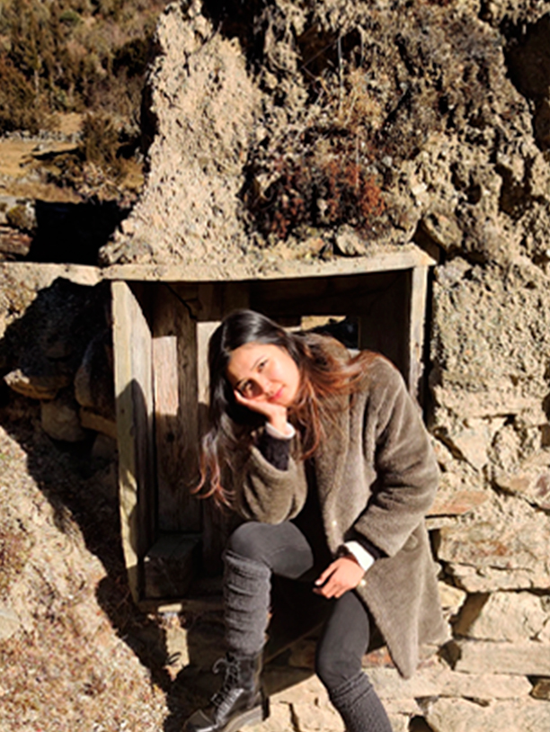 A young woman posing in front of a wooden plank on a rock formation.