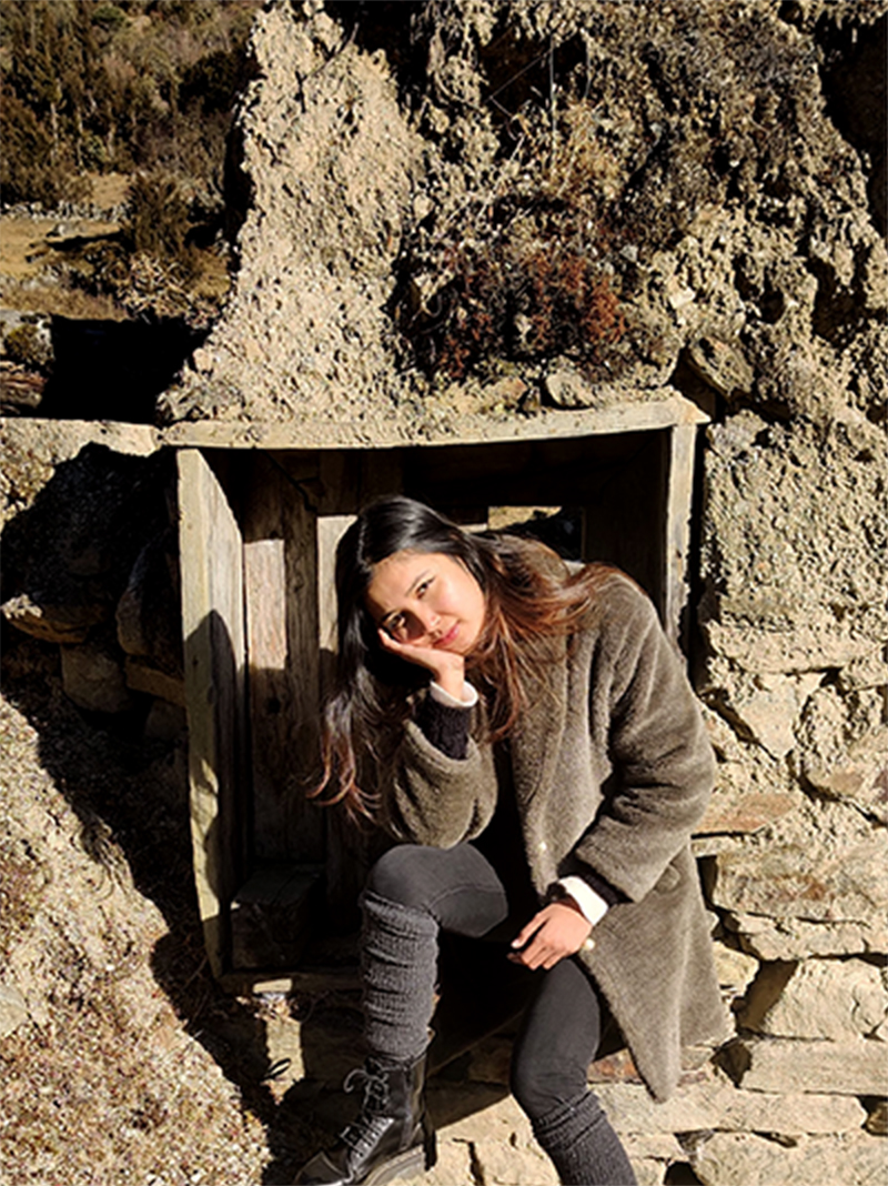 A young woman posing in front of a wooden plank on a rock formation.