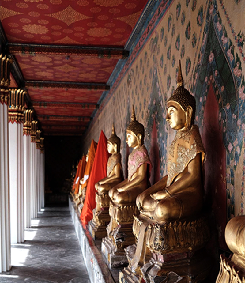 Several bronze Buddha statues are displayed in a row inside the Buddhist temple Wat Arun.