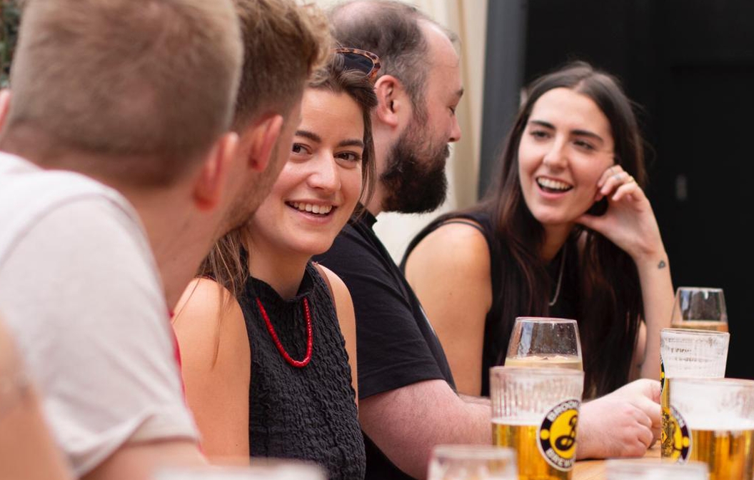 People sharing lively conversations and smiles over glasses of beer, radiating warmth and a vibrant atmosphere.