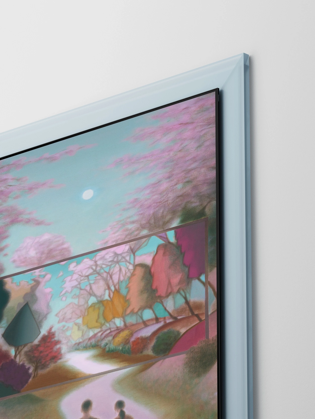 Inside a translucent mint-colored glass frame, The Frame Pro, a thin horizontal screen, sits at the center of a tall spring landscape. A forest path and cherry blossoms appear on the screen, while two people holding hands walk below among softly drifting petals.