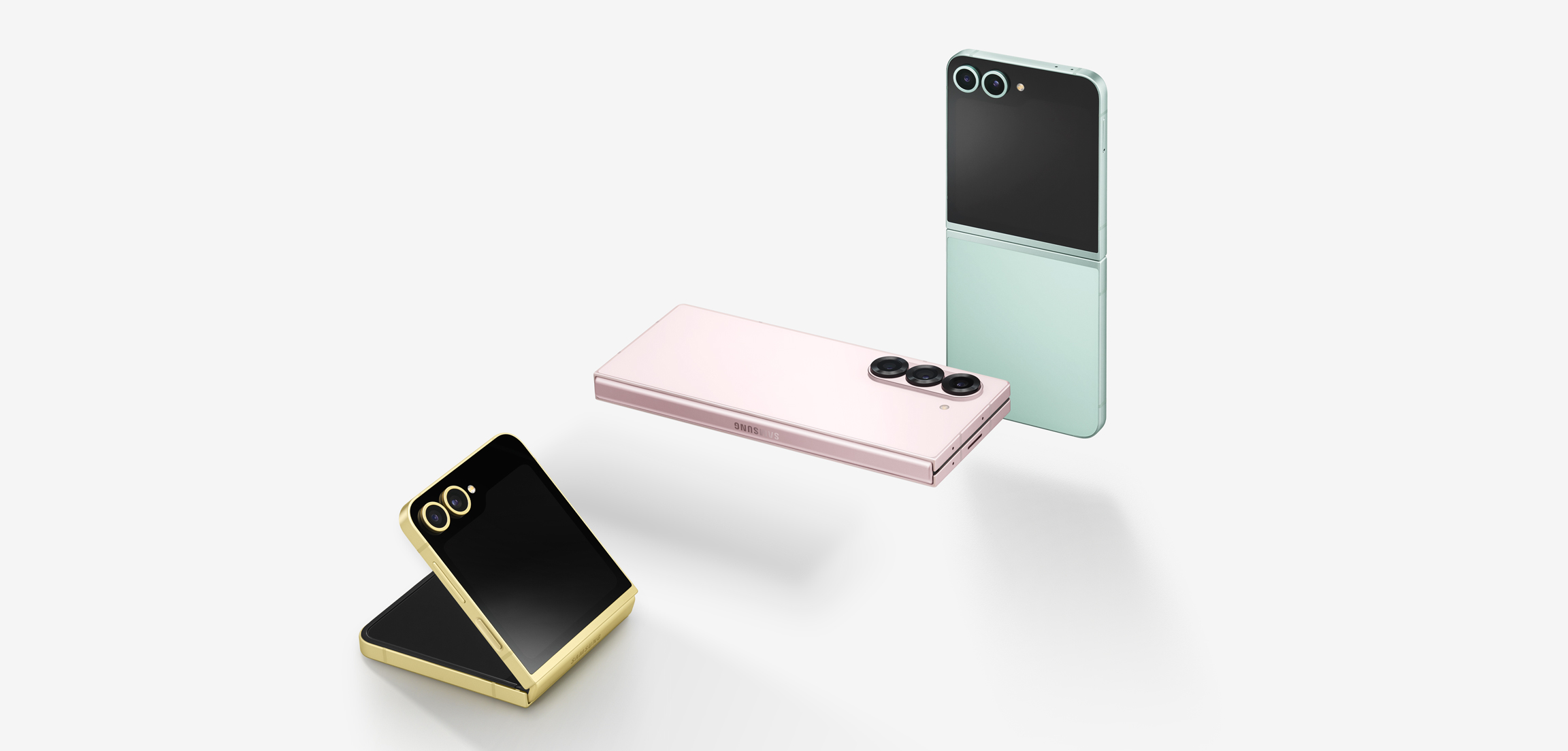The product images are aligned diagonally at 2 o'clock. The Galaxy Z Flip 6 Yellow on the far left is lying on the ground, slightly open. Behind it is the Z Fold 6 Pink, which is fully closed and visible to the camera, lying and floating, and behind it is the Z Flip 6 Mint, which is fully open and visible to the camera, standing in the air.
