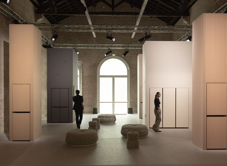 Bespoke of the same material as the pillar is placed inside the huge pillar sculpture, and two young men and women are walking between the pillars, respectively