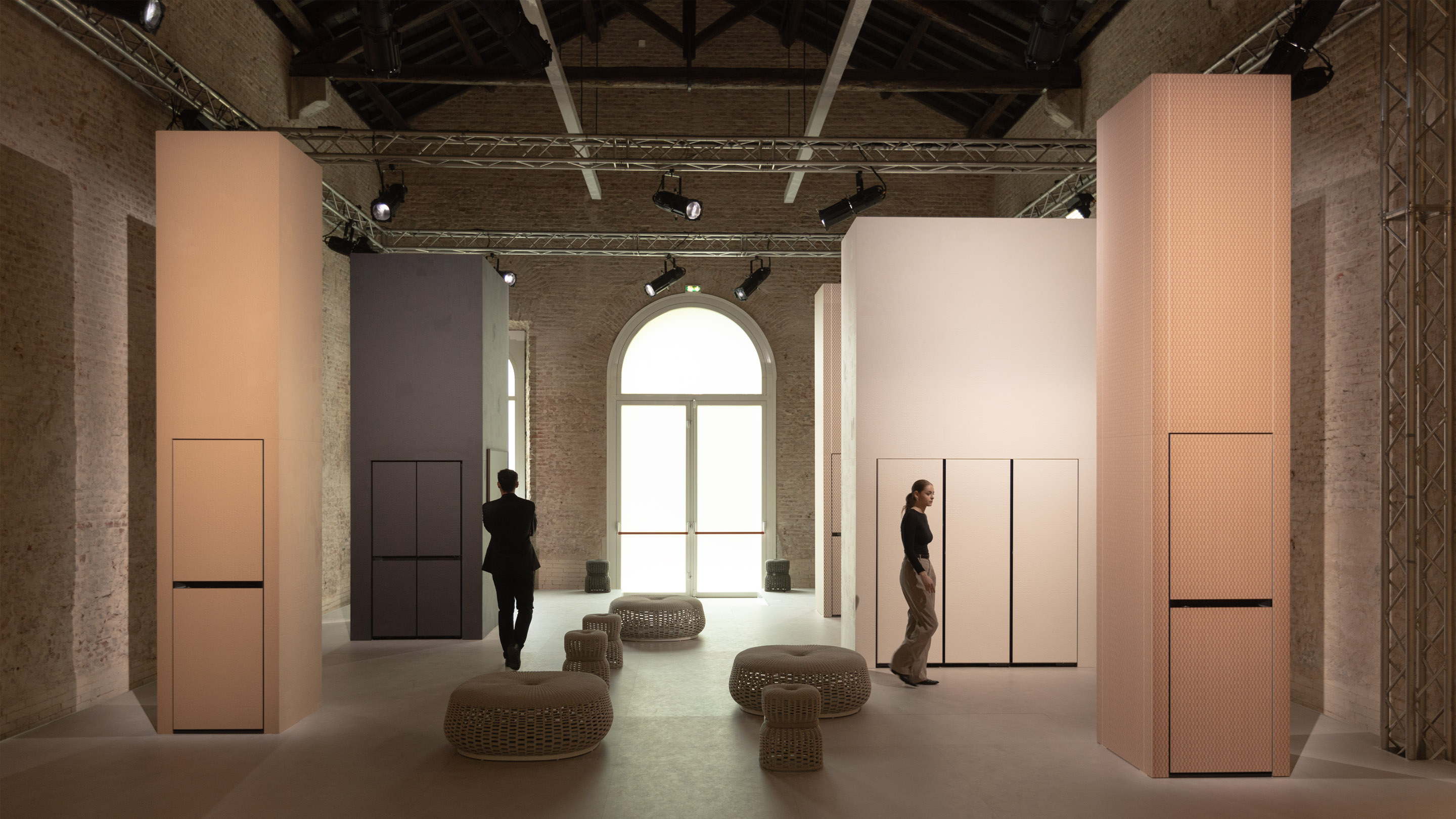 Bespoke of the same material as the pillar is placed inside the huge pillar sculpture, and two young men and women are walking between the pillars, respectively