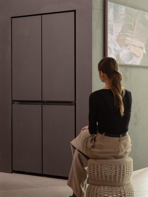 A white woman sits on a stool and observes a Bespoke sculpture in an understated color