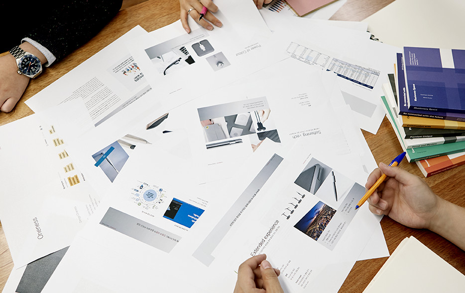 Many books and materials are scattered on a table during a meeting.