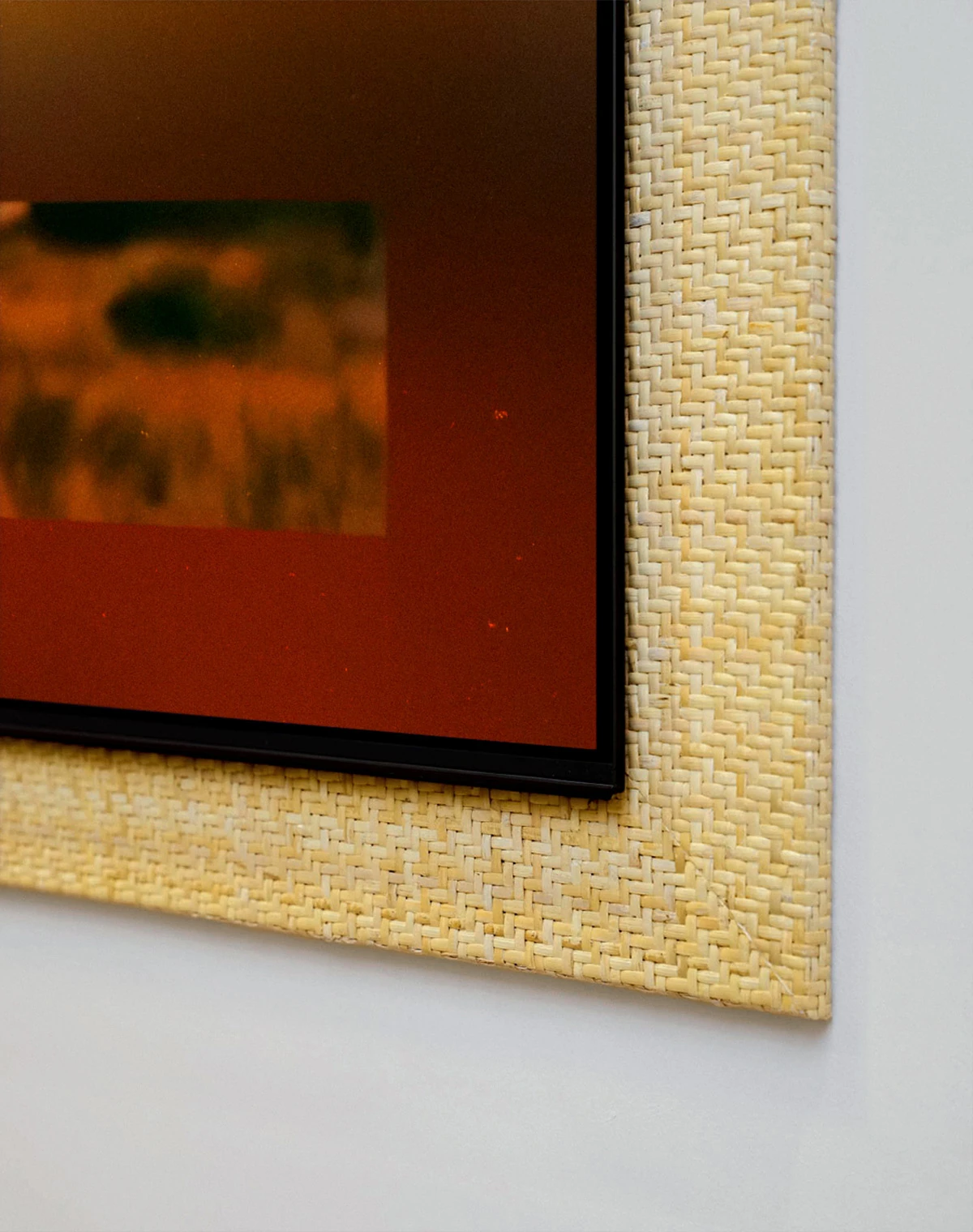 A screen with blue and silver light fills a light beige woven frame. At its center, a Galaxy Z Fold8 opens like a book, displaying a grid of small images of nature, cities, and people.