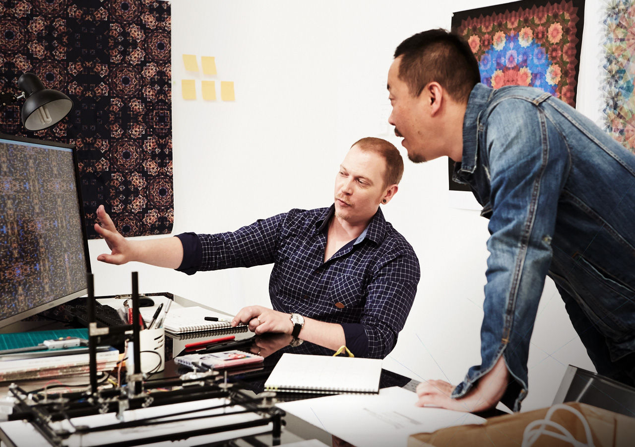 Photographer Jono Lee Graphic Artist Damien Borowick look at a design displayed on the UD970 monitor