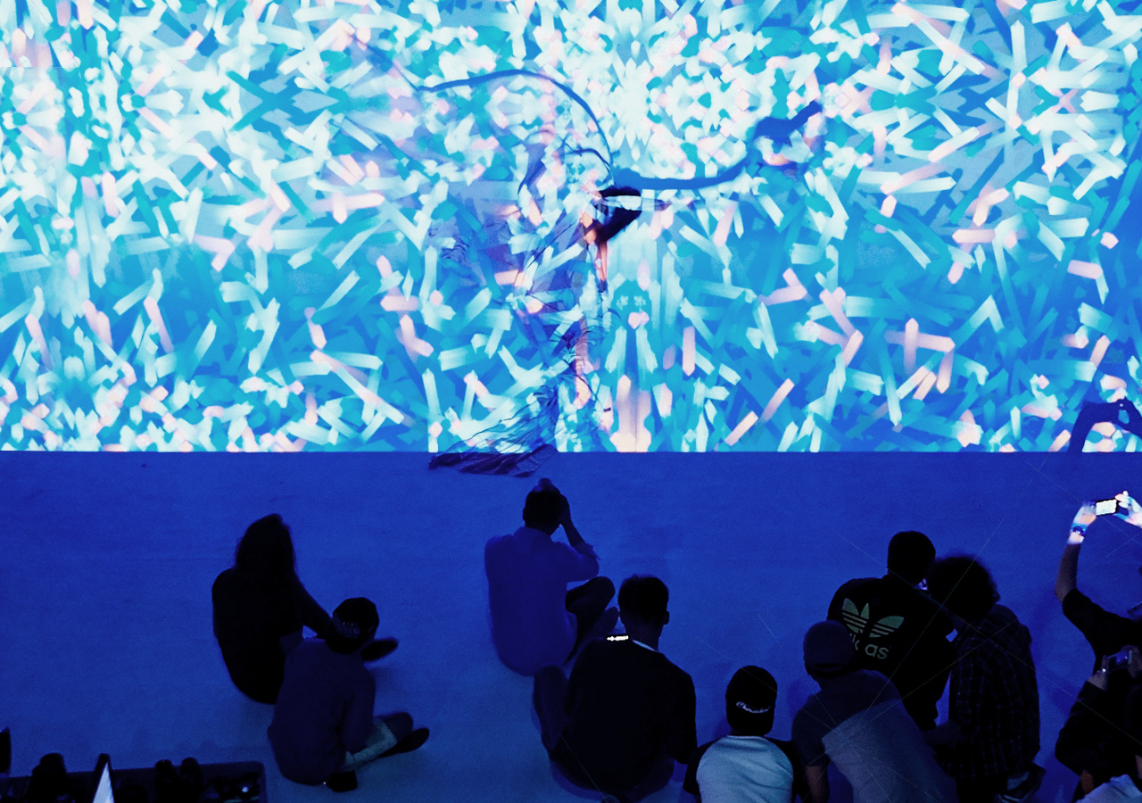 An image shows a photographer taking a picture as a digital image is projected on the model