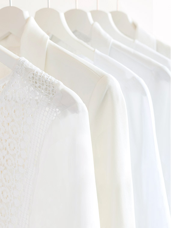 흰색 상의들이 옷걸이에 걸려있습니다.
